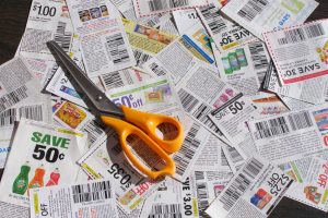 a mass of discount coupons lying on a table with a pair of scissors sitting on top of them