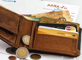 brown wallet lying open showing paper money coins and credit cards