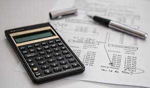 financial calculator sitting on top of financial statements with a pen nearby